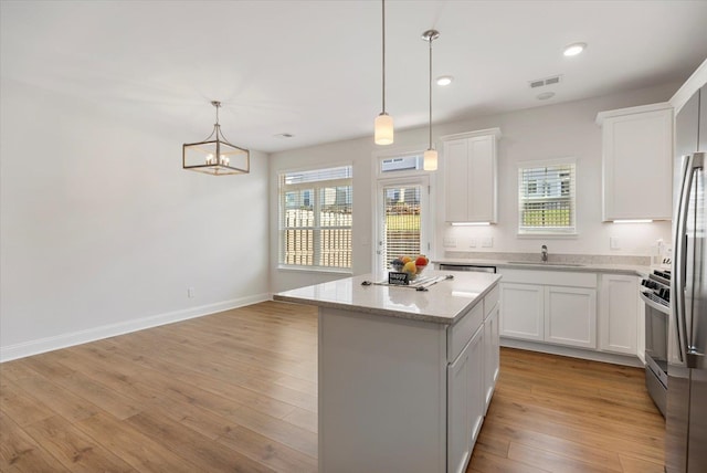 kitchen with light wood-type flooring, sink, a center island, and white cabinets