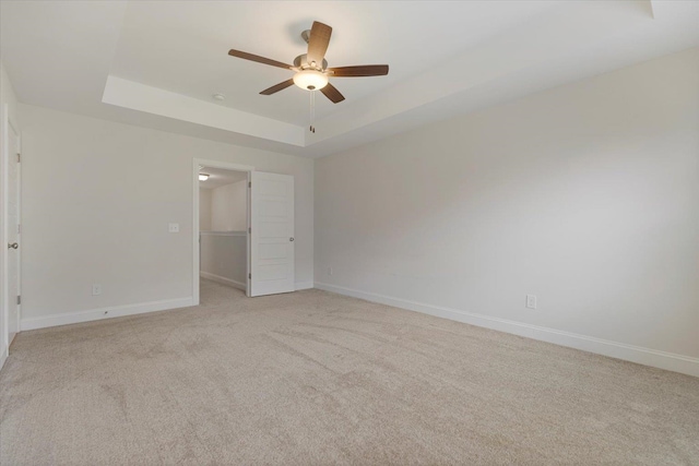 carpeted empty room featuring a raised ceiling and ceiling fan