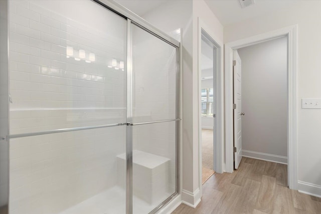 bathroom with wood-type flooring and an enclosed shower