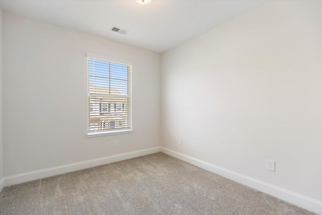 spare room featuring baseboards, visible vents, and light colored carpet