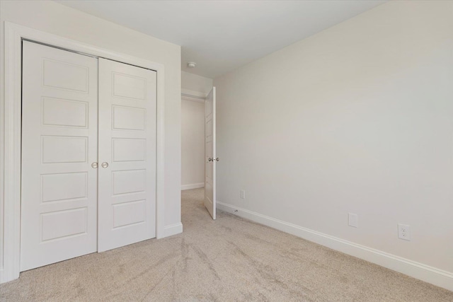 unfurnished bedroom featuring light colored carpet and a closet