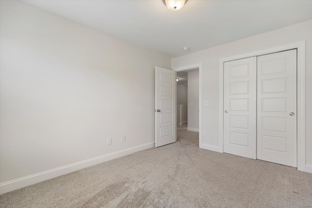 unfurnished bedroom with a closet, carpet flooring, and baseboards