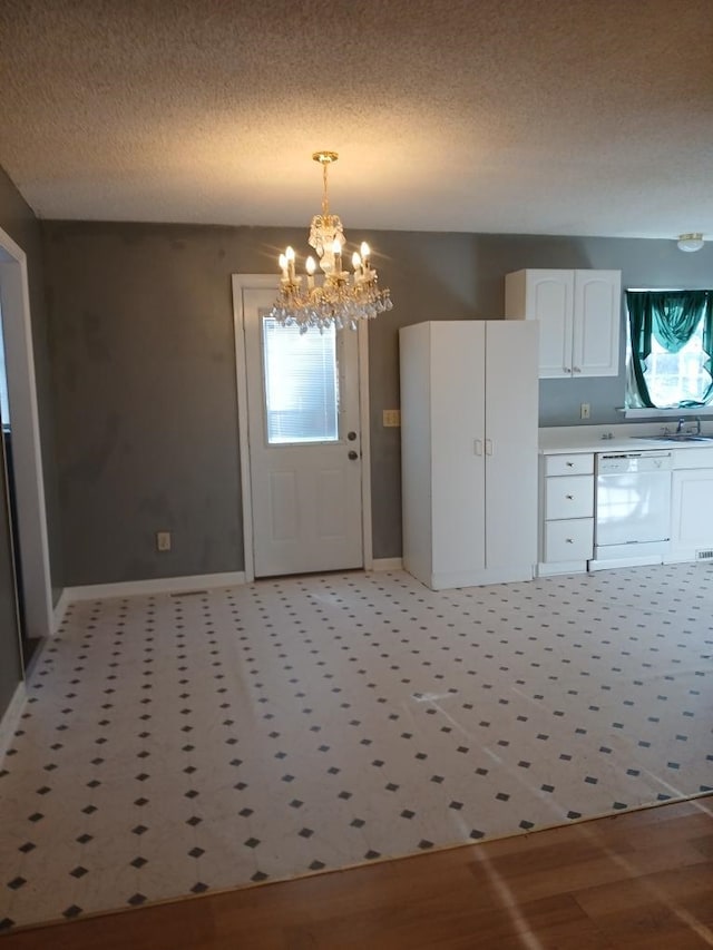 kitchen featuring dishwasher, a chandelier, pendant lighting, a textured ceiling, and white cabinets