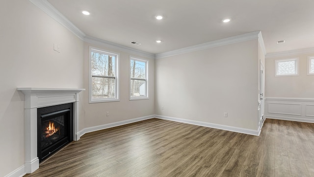 unfurnished living room featuring hardwood / wood-style flooring, ornamental molding, and a healthy amount of sunlight