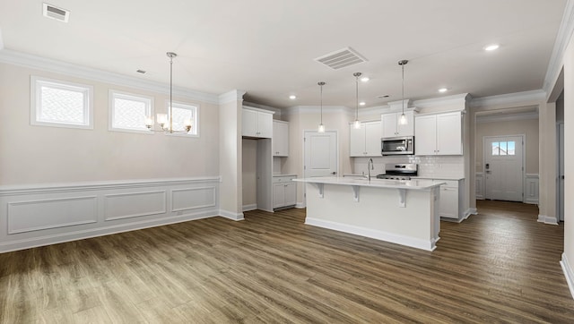 kitchen featuring stainless steel appliances, an island with sink, pendant lighting, and white cabinetry