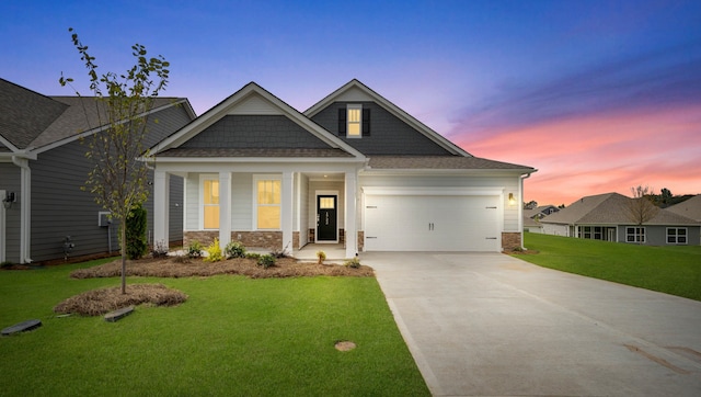 craftsman-style house featuring a garage, covered porch, and a lawn