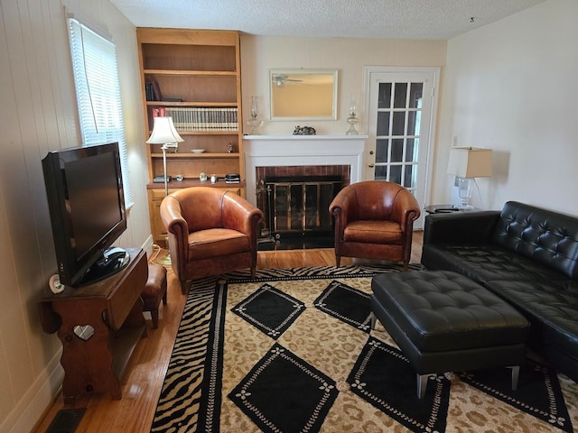 living room with a fireplace, a textured ceiling, and hardwood / wood-style floors