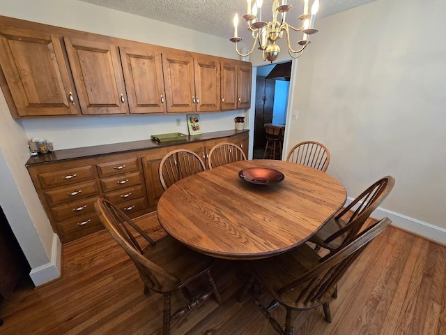 dining room featuring a textured ceiling, dark hardwood / wood-style floors, and a chandelier