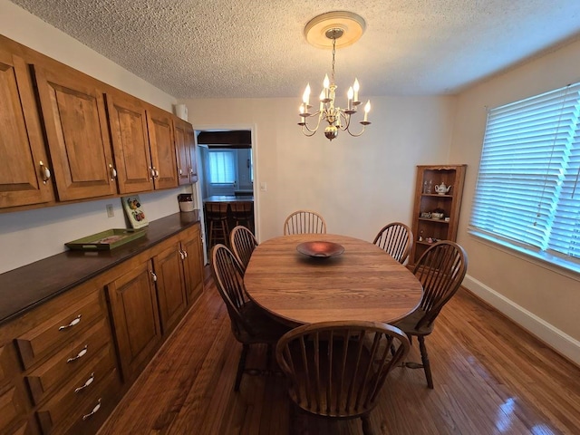 dining room with a textured ceiling, a notable chandelier, and dark hardwood / wood-style floors