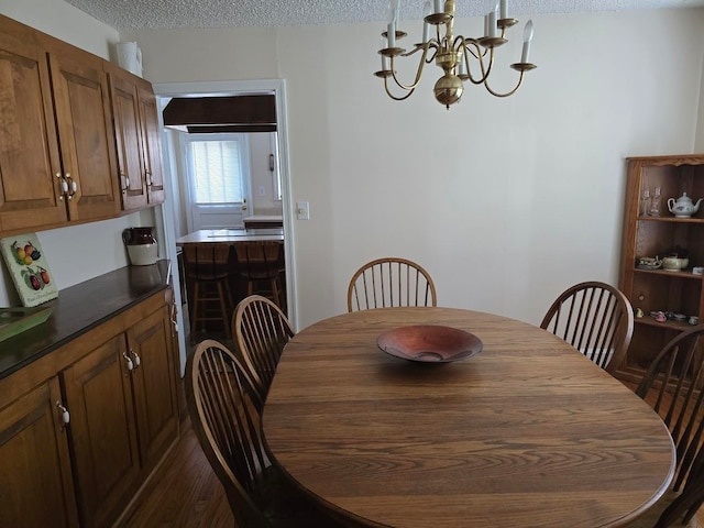 dining area with a textured ceiling, a chandelier, and wood-type flooring