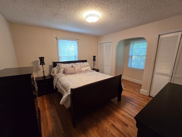 bedroom featuring multiple closets, dark hardwood / wood-style flooring, and a textured ceiling