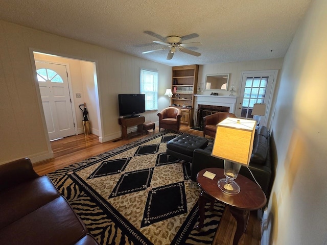 living room featuring a textured ceiling, a wealth of natural light, light hardwood / wood-style flooring, and ceiling fan