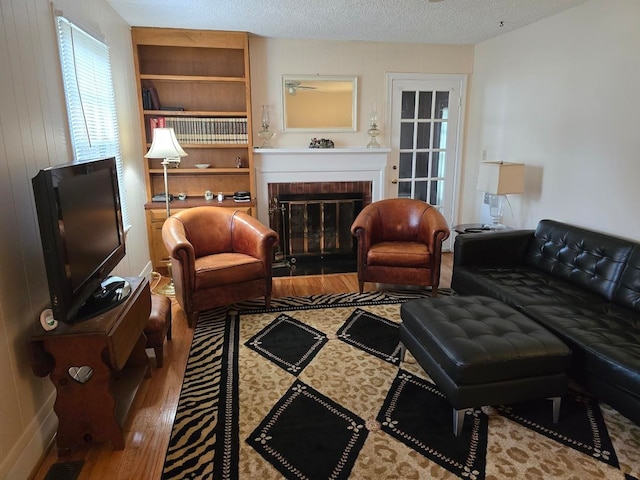 living room featuring a textured ceiling, dark wood-type flooring, and a fireplace