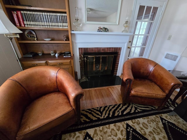 living area with a textured ceiling, ceiling fan, wood-type flooring, and a fireplace