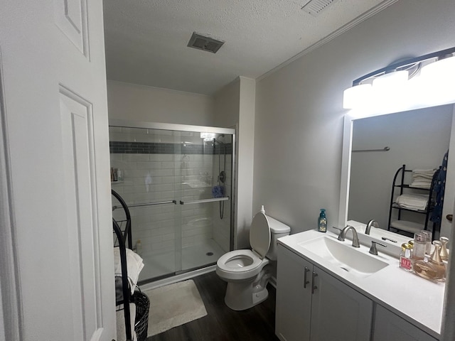 bathroom with a textured ceiling, vanity, a shower with shower door, wood-type flooring, and toilet