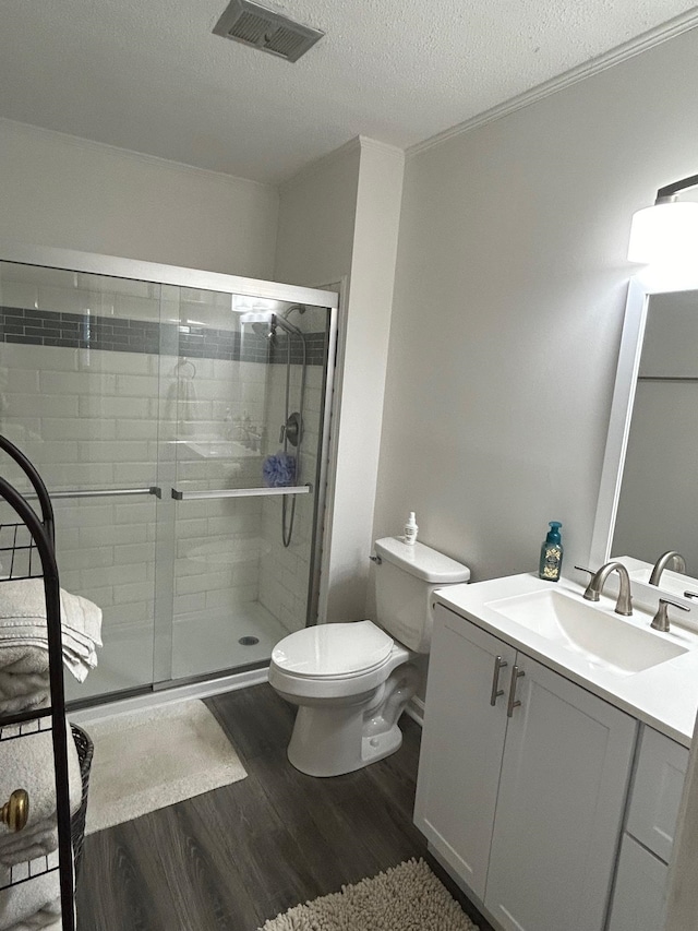 bathroom with a shower with door, hardwood / wood-style flooring, toilet, vanity, and a textured ceiling