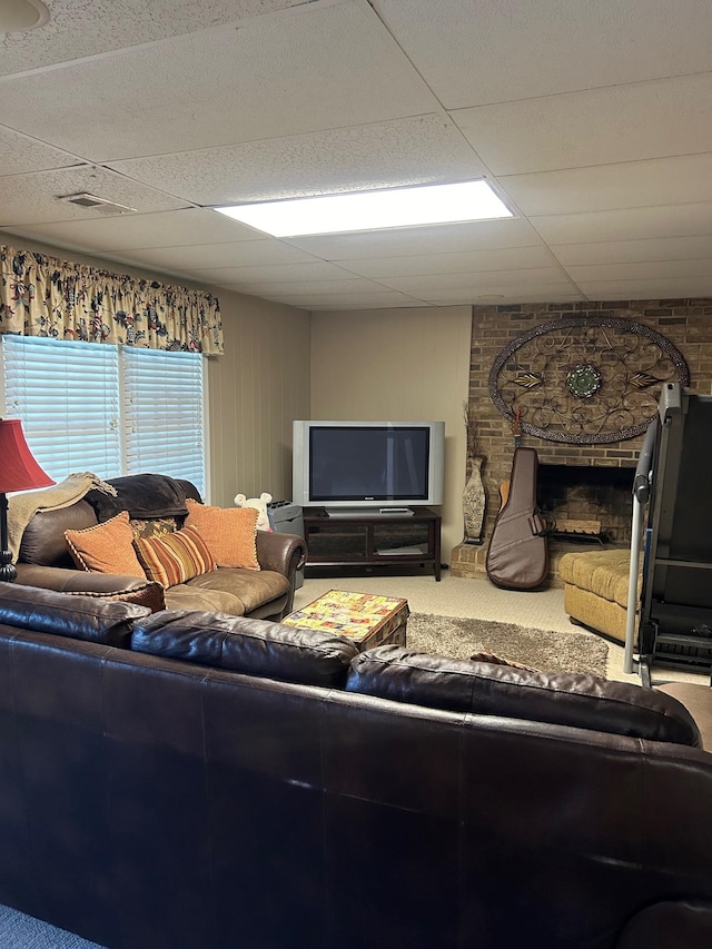 carpeted living room featuring a paneled ceiling and a stone fireplace