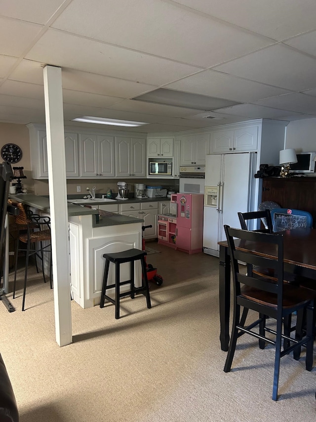 kitchen featuring white appliances, a paneled ceiling, sink, and carpet floors