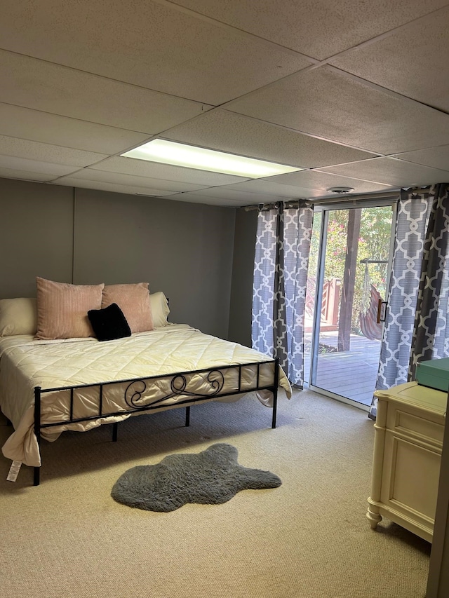 carpeted bedroom featuring access to exterior and a drop ceiling