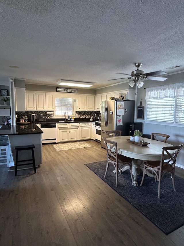 dining space with a textured ceiling, ceiling fan, sink, and hardwood / wood-style flooring