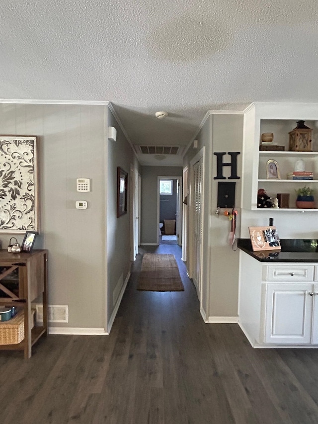 corridor with ornamental molding, a textured ceiling, and dark hardwood / wood-style floors