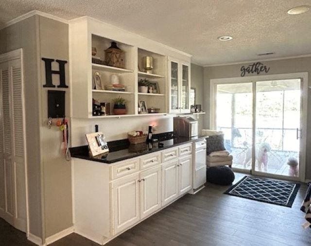 bar featuring crown molding, a textured ceiling, white cabinetry, and dark hardwood / wood-style floors