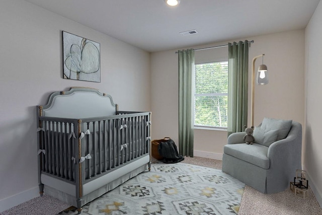 bedroom with light colored carpet and a nursery area