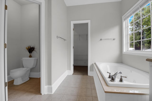 bathroom with tile patterned flooring, toilet, a healthy amount of sunlight, and tiled bath