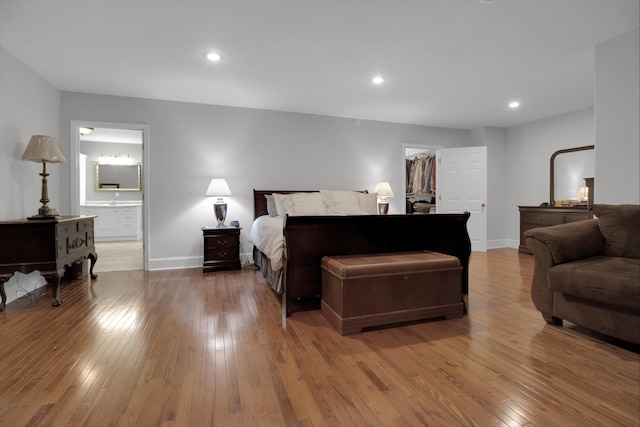 bedroom with light wood-type flooring, connected bathroom, a spacious closet, and a closet