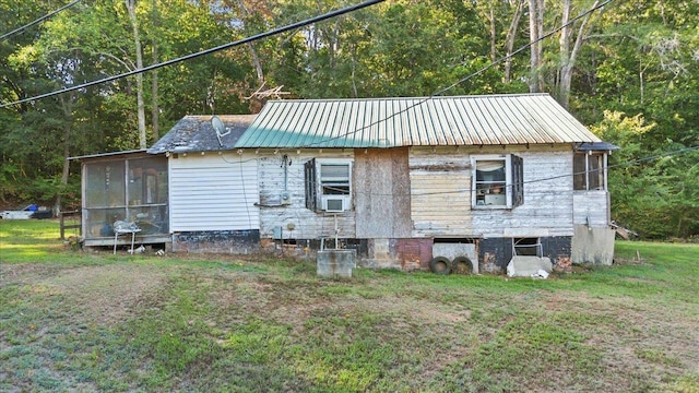 exterior space featuring a sunroom, metal roof, cooling unit, a yard, and a wooded view