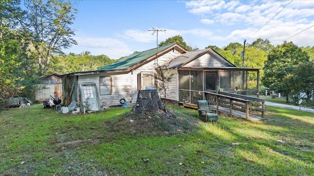 back of property with a sunroom and a lawn