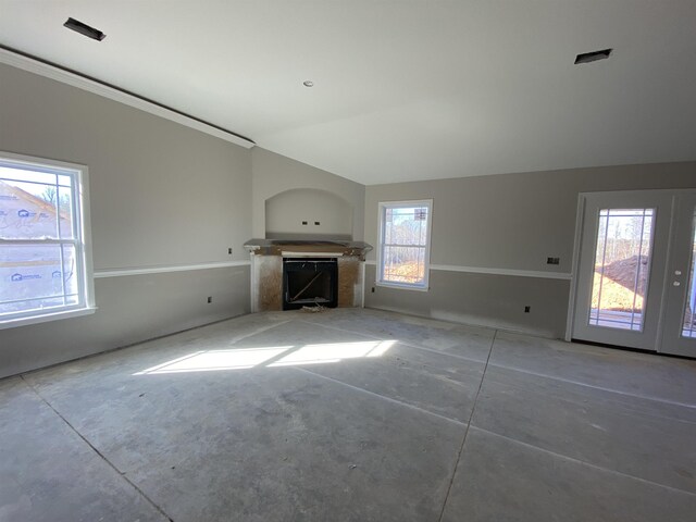 unfurnished living room with vaulted ceiling, a fireplace, and unfinished concrete flooring