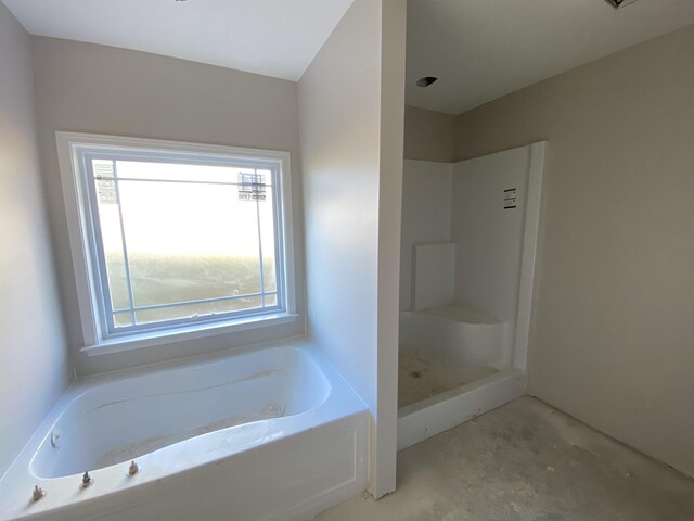 bathroom featuring concrete flooring, walk in shower, and a bath