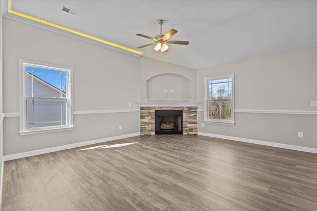 unfurnished living room with visible vents, a stone fireplace, baseboards, and wood finished floors