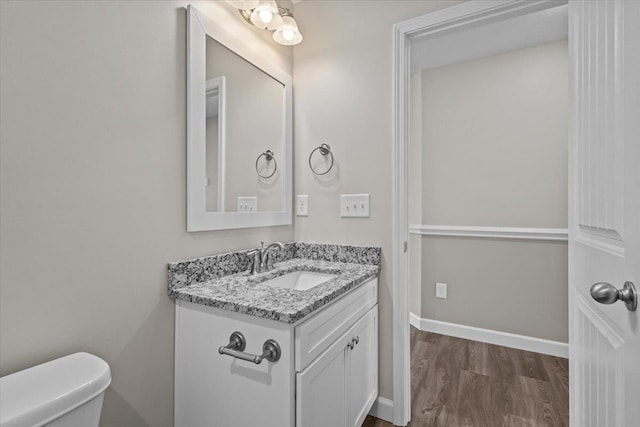 bathroom with baseboards, vanity, toilet, and wood finished floors