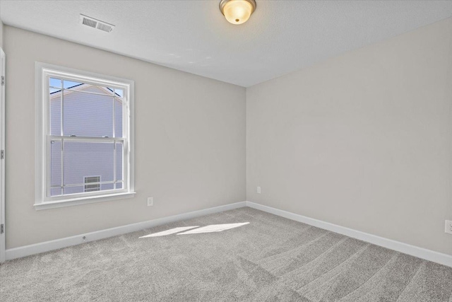 carpeted empty room featuring visible vents, baseboards, and a textured ceiling