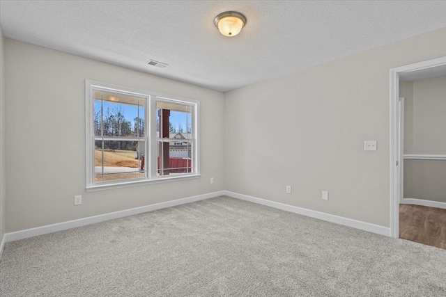 carpeted empty room with a textured ceiling, visible vents, and baseboards