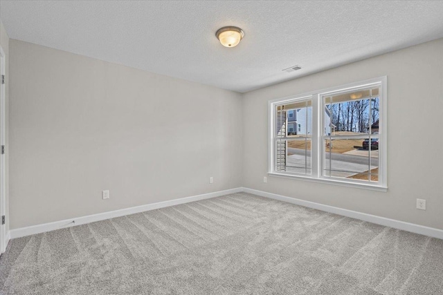 carpeted empty room with visible vents, baseboards, and a textured ceiling