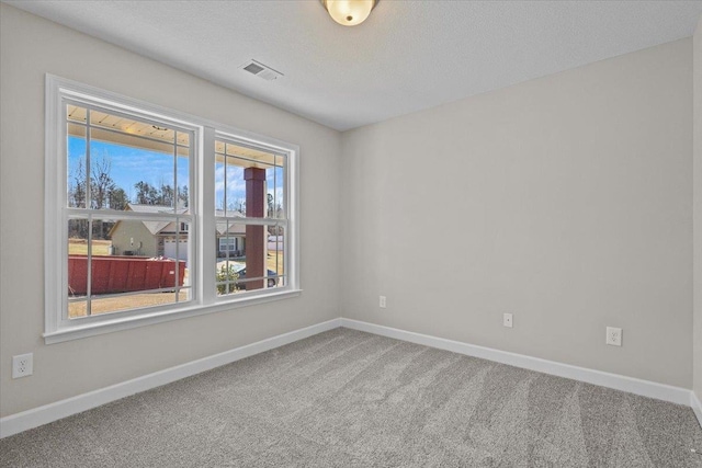 empty room featuring carpet floors, baseboards, visible vents, and a textured ceiling