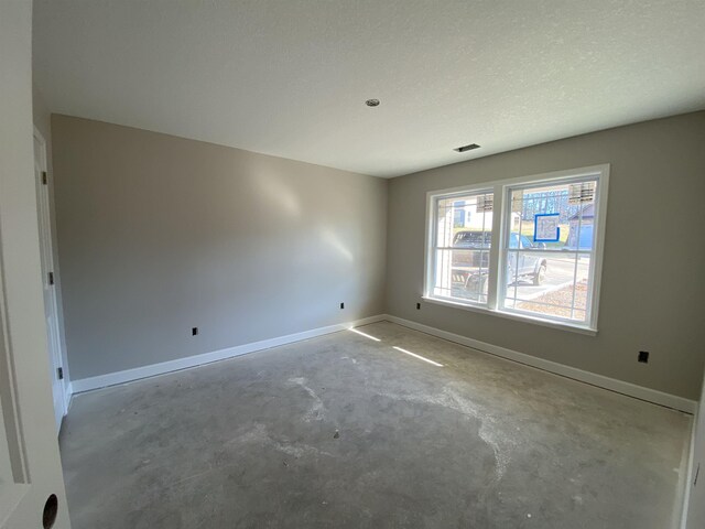 unfurnished room featuring visible vents, unfinished concrete floors, and baseboards