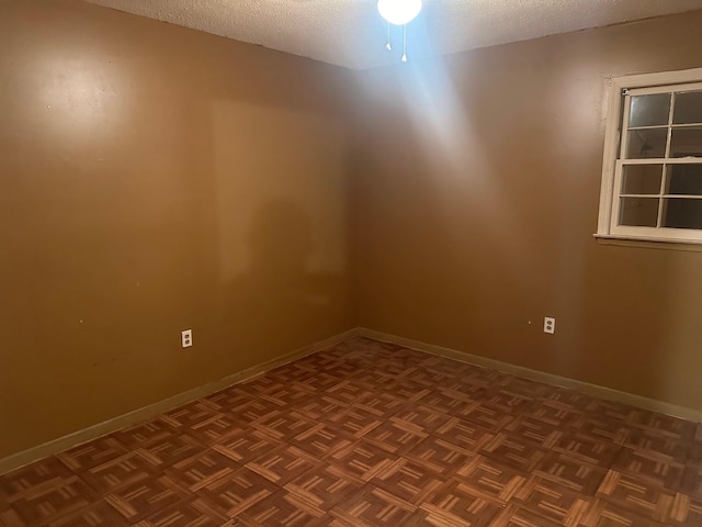 empty room featuring a textured ceiling, ceiling fan, and parquet flooring