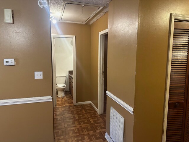 corridor with a textured ceiling and dark parquet flooring