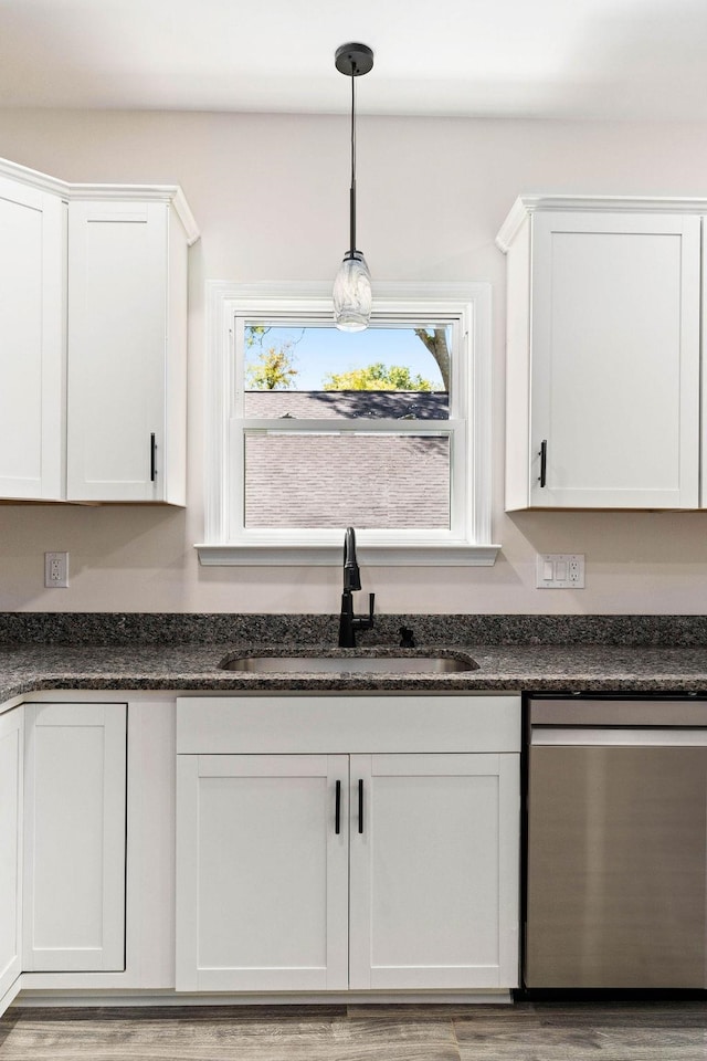 kitchen with white cabinetry, sink, hanging light fixtures, stainless steel dishwasher, and light hardwood / wood-style floors