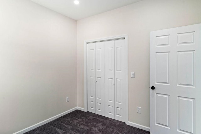 unfurnished bedroom featuring dark carpet and a closet