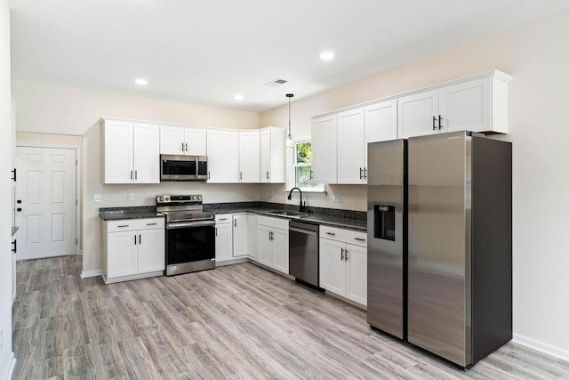 kitchen with hanging light fixtures, light wood-type flooring, sink, and appliances with stainless steel finishes