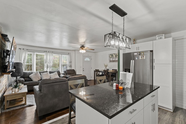 kitchen featuring a kitchen island, a breakfast bar area, dark hardwood / wood-style flooring, stainless steel refrigerator with ice dispenser, and ceiling fan