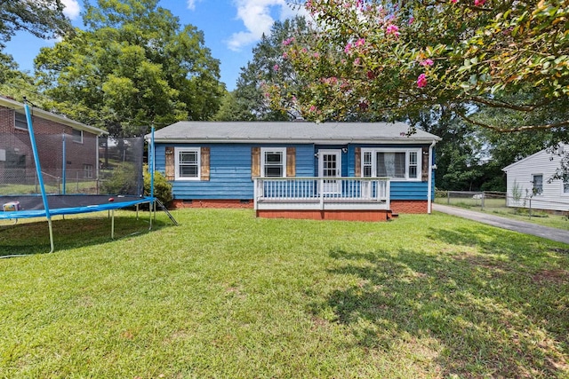 view of front of home featuring a trampoline, a wooden deck, and a front lawn