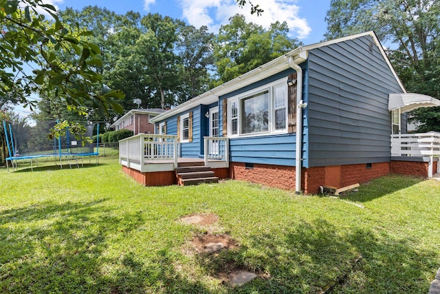 exterior space featuring a front lawn, a trampoline, and a deck