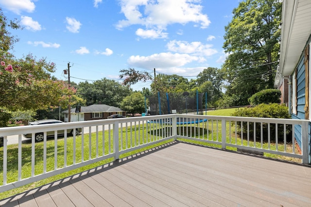 wooden deck with a trampoline and a lawn