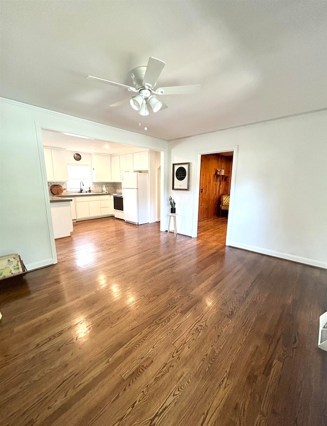 unfurnished living room featuring dark hardwood / wood-style flooring, sink, and ceiling fan